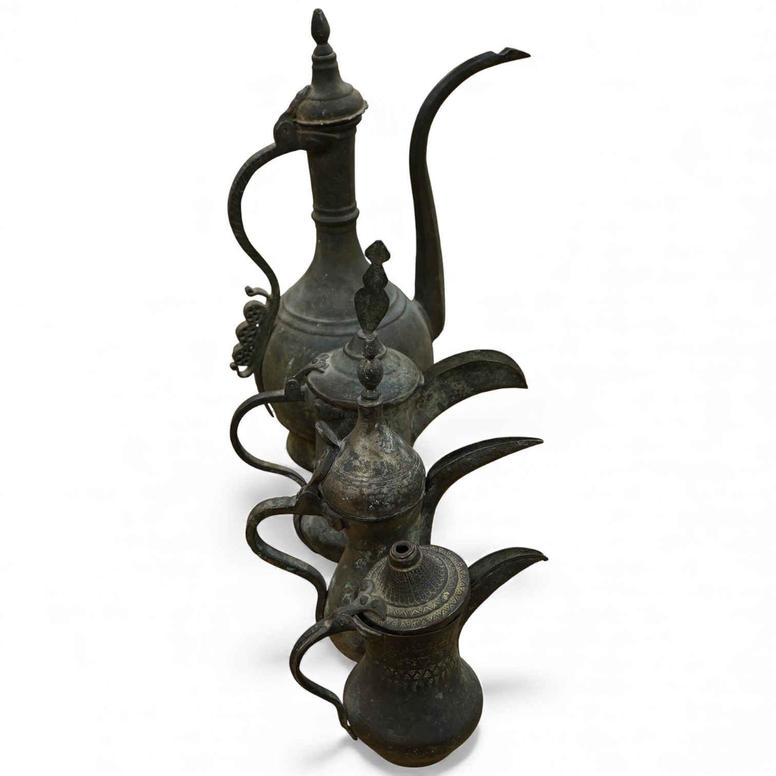 Three Arabic dallahs, two brass, one copper and a copper coffee ewer, 45cm